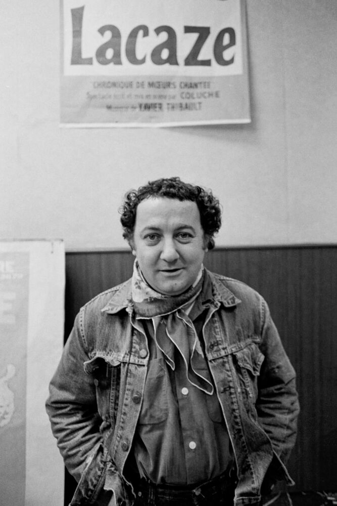 Coluche devant l'affiche de son spectacle "Ginette Lacaze", 1977